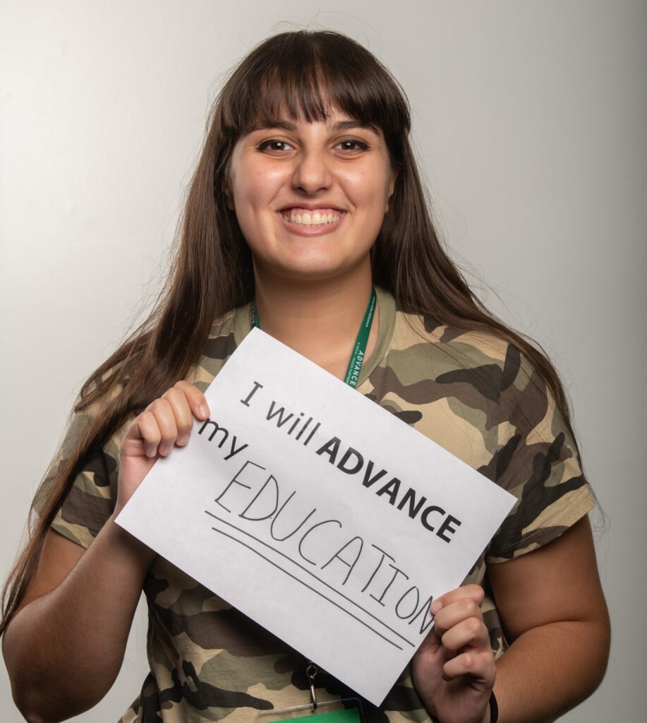 Female Mason student holding a sign with text written on it that says, "I will ADVANCE my education"